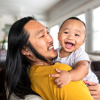Asian American father hugging his son
