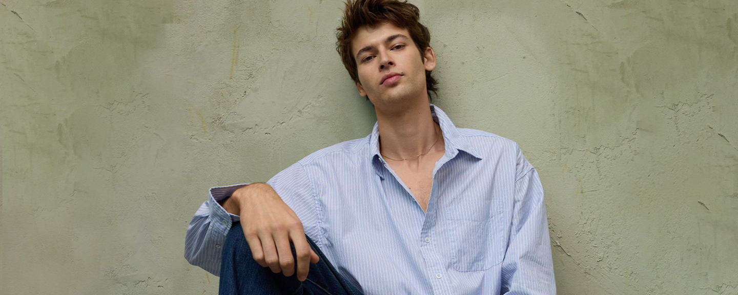 A young man leans against a wall sitting on the floor