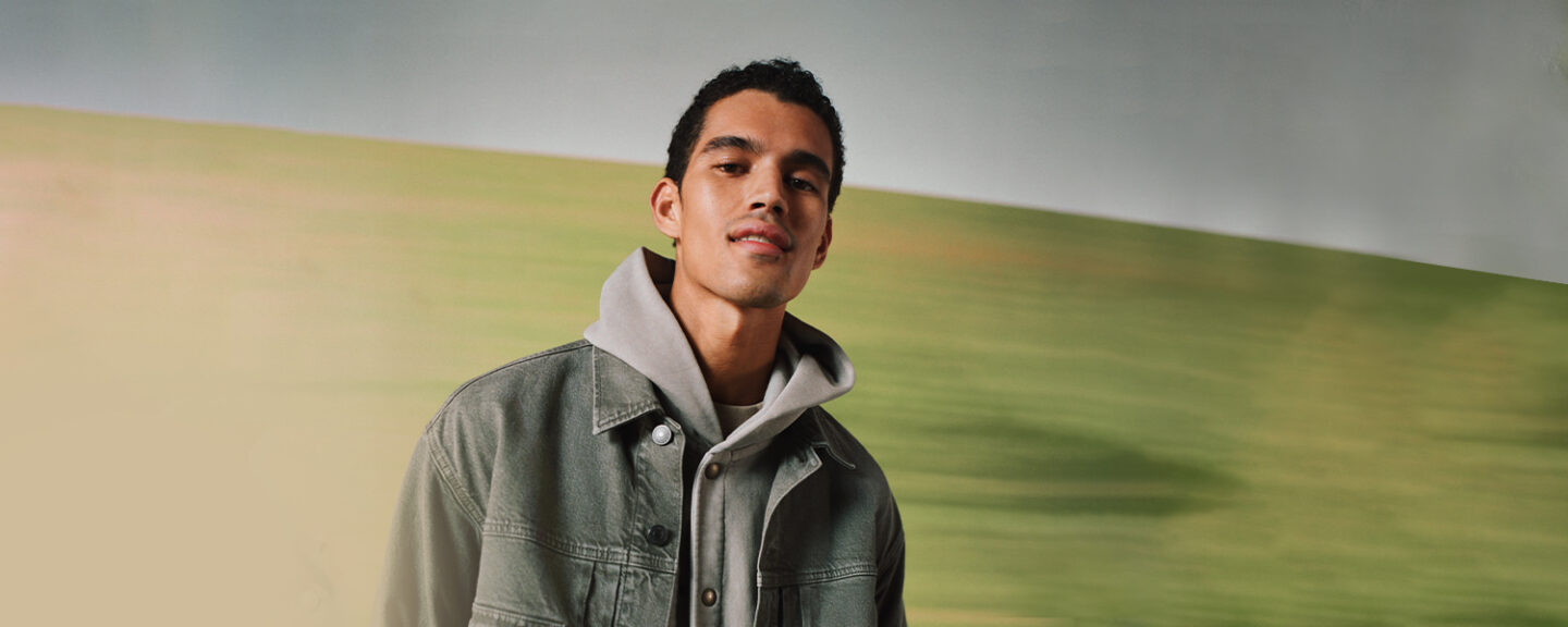 A young black man standing in front of a green wall