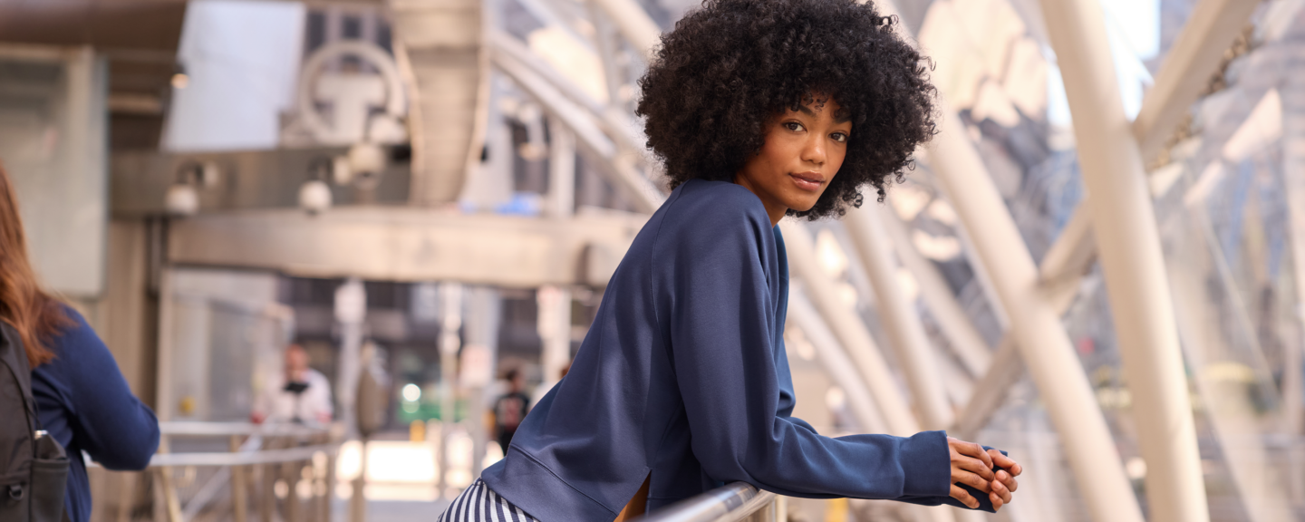 A black woman leans on a railing in the city