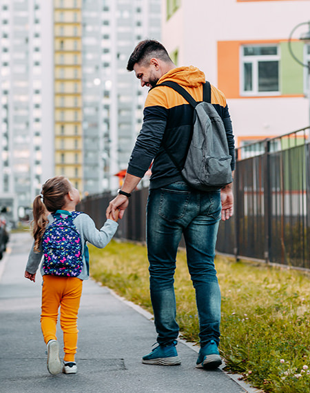 Father and young daughter walk together to school