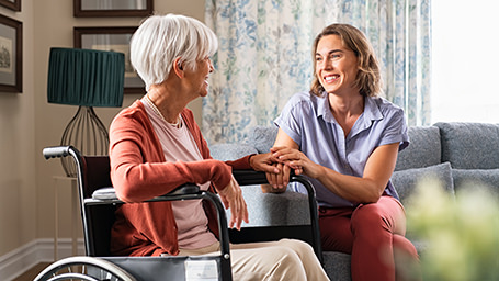 Adult daughter speaks to her elderly mother who sits in a wheelchair