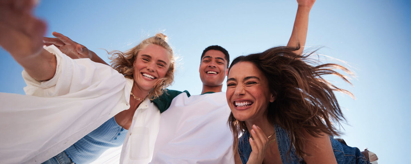 Three friends smile in the sunshine