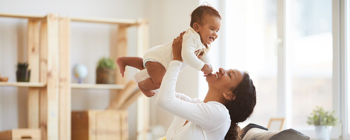 A black mom lifts up her baby boy