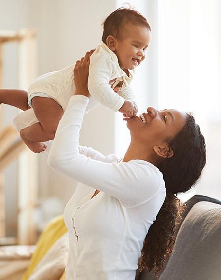 A black mom lifts up her baby boy